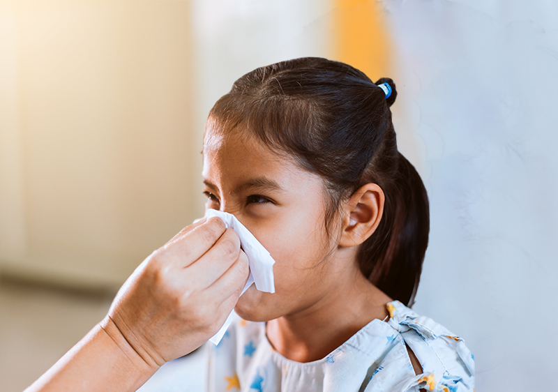 child blowing nose into tissue